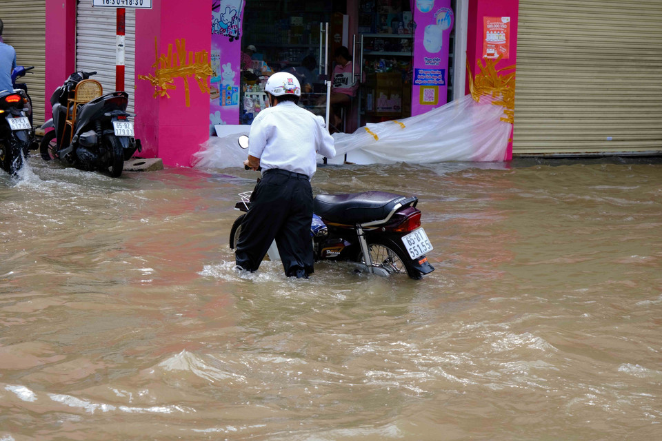 Người dân phải dắt bộ do xe máy bị ngập nước, chết máy. (Ảnh: Thanh Liêm/TTXVN)