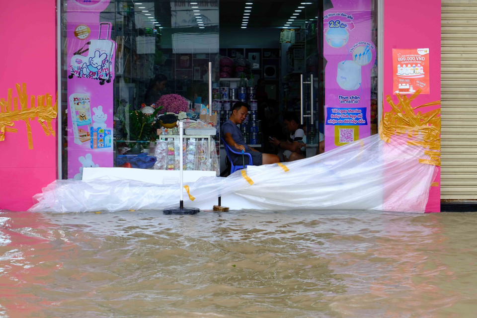 Một cửa hàng trên đường Trần Hưng Đạo dùng bạt cao su ngăn nước tràn vào nhà. (Ảnh: Thanh Liêm/TTXVN)