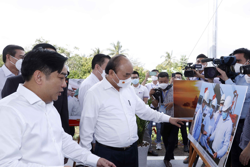 Hình ảnh Chủ tịch nước Nguyễn Xuân Phúc xem trưng bày ảnh quá trình thi công Dự án tuyến đường cao tốc Trung Lương-Mỹ Thuận. (Ảnh: Thống Nhất/TTXVN)