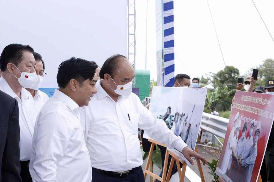 Chủ tịch nước Nguyễn Xuân Phúc xem trưng bày ảnh quá trình thi công Dự án tuyến đường cao tốc Trung Lương-Mỹ Thuận. (Ảnh: Thống Nhất/TTXVN)