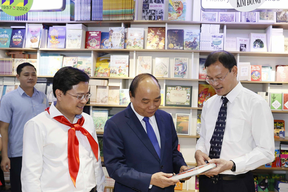 Chủ tịch nước Nguyễn Xuân Phúc và các đại biểu tham quan trưng bày Dấu ấn 65 năm Nhà xuất bản Kim Đồng. (Ảnh: Thống Nhất/TTXVN)