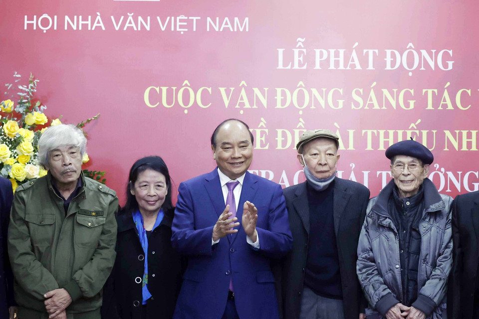 Chủ tịch nước Nguyễn Xuân Phúc tặng quà cho các nhà văn.(Ảnh: Thống Nhất/TTXVN)