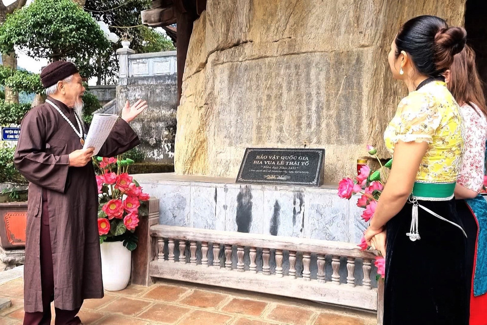 Thủ nhang Vũ Phong Oanh, ở xã Lê Lợi, huyện Nậm Nhùn giới thiệu cho du khách về bảo vật quốc gia bia Lê Thái Tổ. (Ảnh: Nguyễn Oanh/TTXVN)