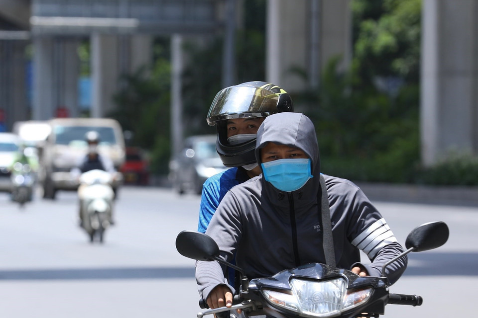 Người dân Hà Nội mặc kín mít khi phải di chuyển trên đường giữa trời nắng nóng. (Ảnh: Hoàng Hiếu/TTXVN)