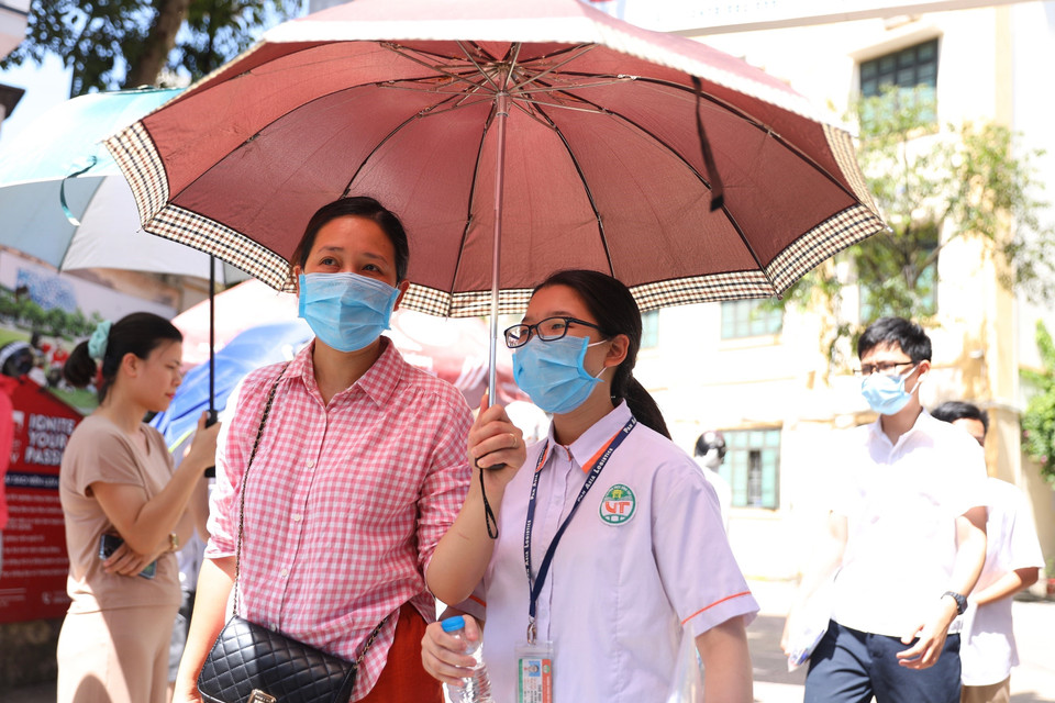 Phụ huynh đón con em đi thi dưới thời tiết nắng nóng. (Ảnh: Hoàng Hiếu/TTXVN)