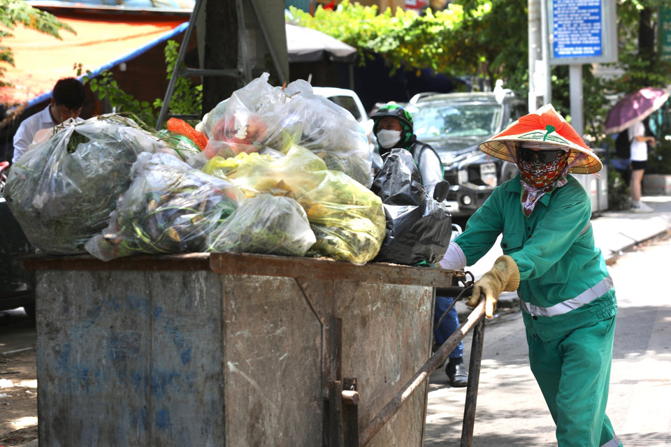 Công nhân môi trường Hợp tác xã Thành Công vẫn cần mẫn làm việc trên phố Nguyễn Trãi giữa trưa nóng. (Ảnh: Hoàng Hiếu/TTXVN)