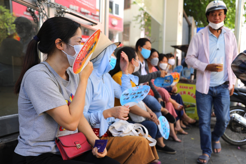 Quạt là vật dụng không thể thiếu của phụ huynh giữa trời oi bức trong khi chờ thí sinh thi xong. (Ảnh: Hoàng Hiếu/TTXVN)