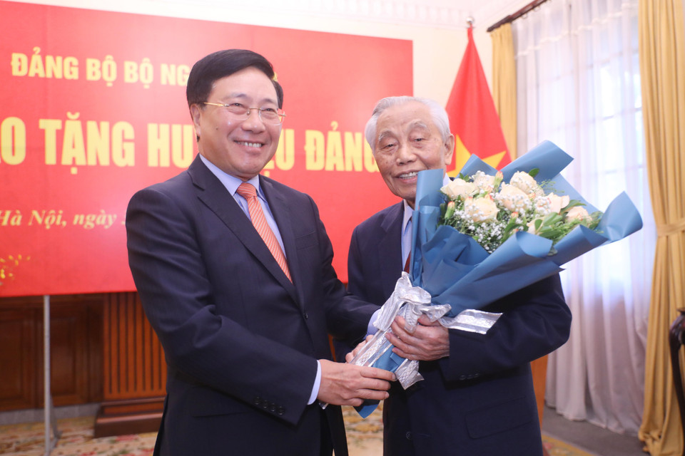 Phó Thủ tướng Thường trực Phạm Bình Minh tặng hoa, chúc mừng ông Nguyễn Mạnh Cầm nhận Huy hiệu 75 năm tuổi Đảng. (Ảnh: Lâm Khánh/TTXVN)