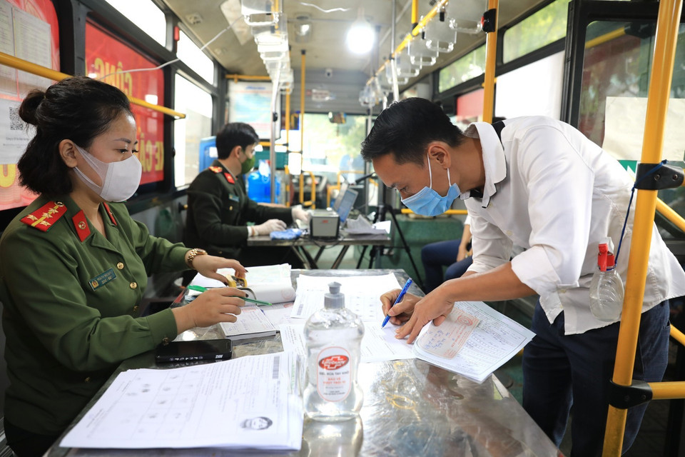 Người dân tới làm căn cước công dân được yêu cầu điền đầy đủ thông tin vào bản điều tra thông tin cá nhân ngay bên trong xe buýt lưu động. (Ảnh: Thành Đạt/TTXVN)