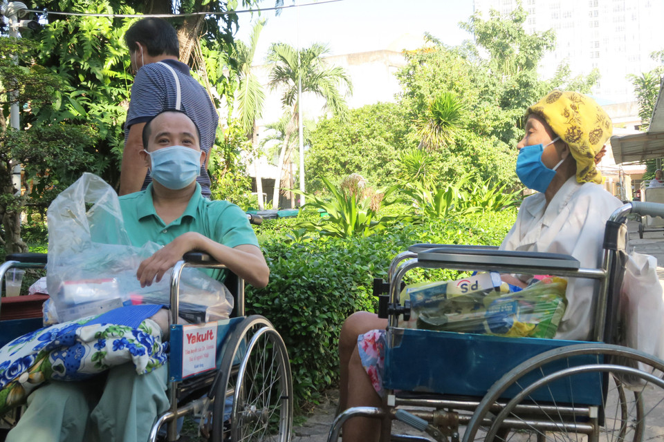 Các bệnh nhân chờ người thân mua hàng tại Phiên chợ 0 đồng. (Ảnh: Đinh Hằng/TTXVN)