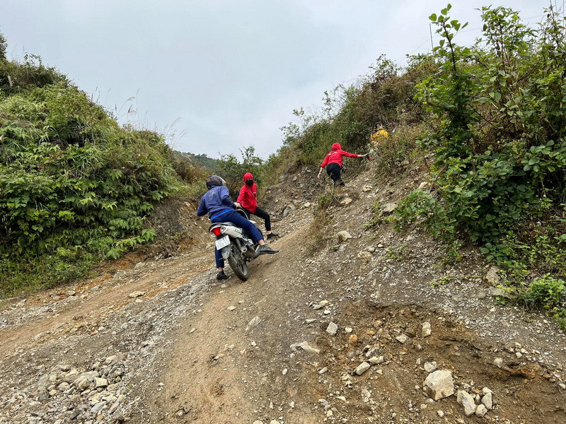 Rất nhiều đoạn dốc không thể đi xe máy, các biên tập viên, phóng viên Báo Điện tử VietnamPlus thành người hỗ trợ kéo, đẩy xe cùng vượt khó để lên bản. (Ảnh: PV/Vietnam+)