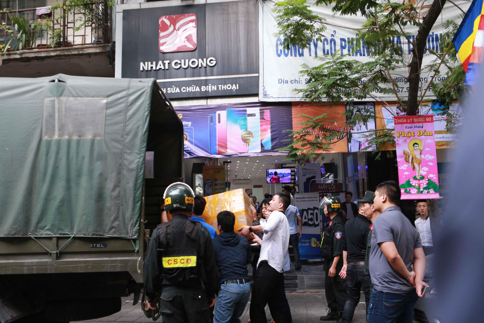 Cảnh sát kiểm tra, khám xét và đưa các kiện hàng lên xe tại cửa hàng điện thoại Nhật Cường mobile ở 33 Lý Quốc Sư, Hà Nội. (Ảnh: Doãn Tấn/TTXVN)