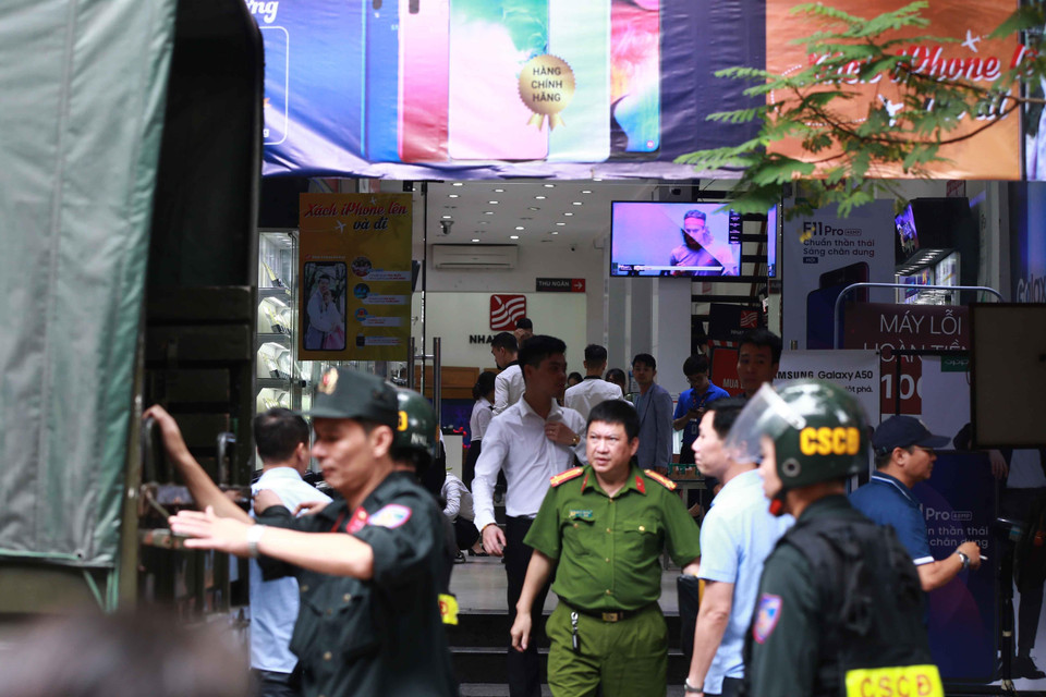 Cảnh sát kiểm tra, khám xét và đưa các kiện hàng lên xe tại cửa hàng điện thoại Nhật Cường mobile ở 33 Lý Quốc Sư, Hà Nội. (Ảnh: Doãn Tấn/TTXVN)