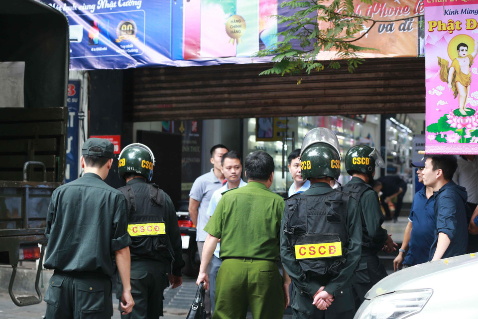 Cảnh sát kiểm tra, khám xét và đưa các kiện hàng lên xe tại cửa hàng điện thoại Nhật Cường mobile ở 33 Lý Quốc Sư, Hà Nội. (Ảnh: Doãn Tấn/TTXVN)