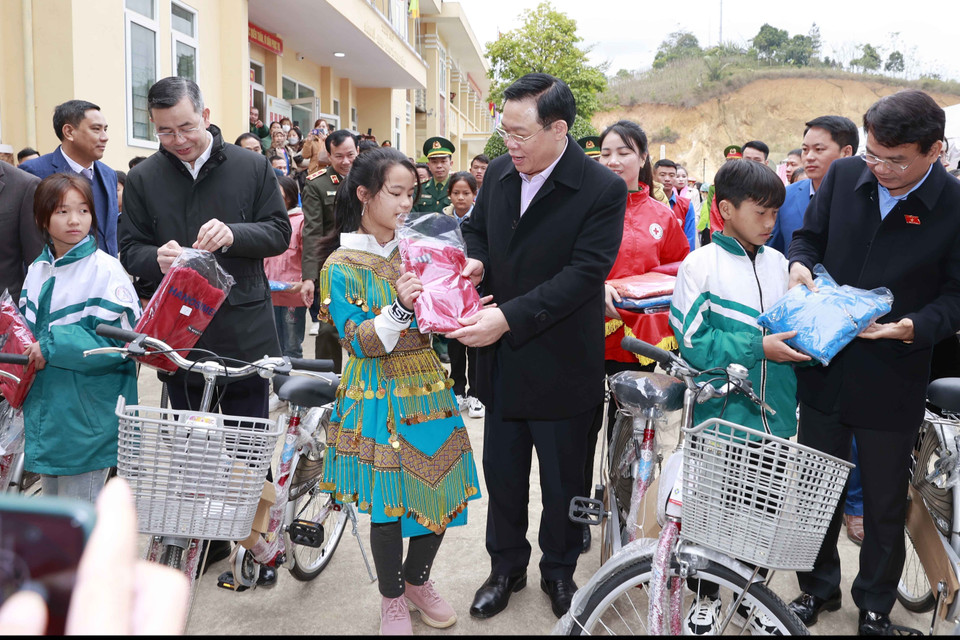 Chủ tịch Quốc hội Vương Đình Huệ tặng xe đạp và chiếc áo ấm cho các em học sinh có hoàn cảnh khó khăn. (Ảnh: Doãn Tấn/TTXVN)