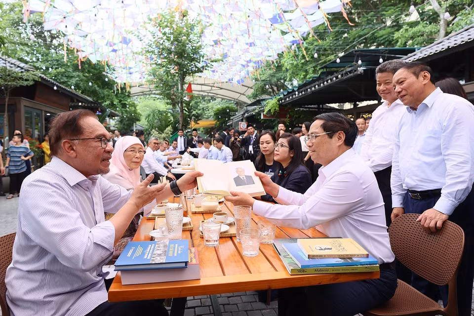 Thủ tướng Phạm Minh Chính tặng sách cho Thủ tướng Malaysia Anwar Ibrahim và Phu nhân. (Ảnh: Dương Giang/TTXVN)