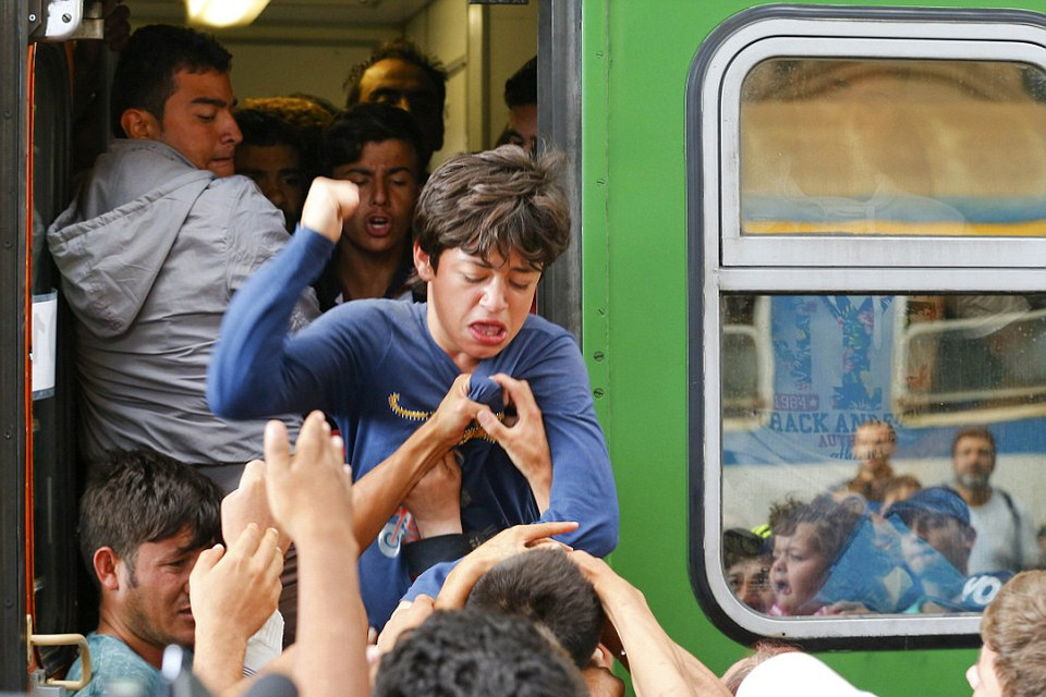 Một thanh niên đang đấm vào những người tị nạn cố kéo cậu xuống tàu. (Nguồn: Dailymail)