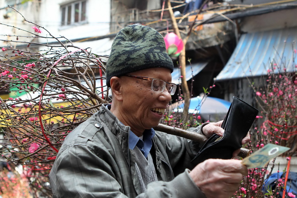 Vui mừng khi tìm mua được cành đào ưng ý. (Ảnh: Quốc Khánh/TTXVN)