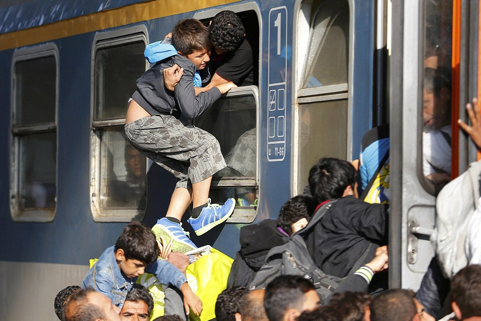 Một đứa bé được nhấc lên qua cửa sổ ở đoàn tàu ở trạm nhà ga Keleti, thủ đô Budapest. (Nguồn: Dailymail)