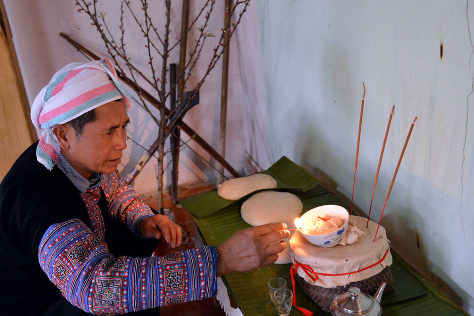 Bày biện ban thờ tổ tiên, gồm ba chiếc bánh dày, ba chén rượu, thắp ba nén nhang; đèn thắp sáng ban thờ bằng mỡ lợn. (Ảnh: Thanh Hà/TTXVN) 