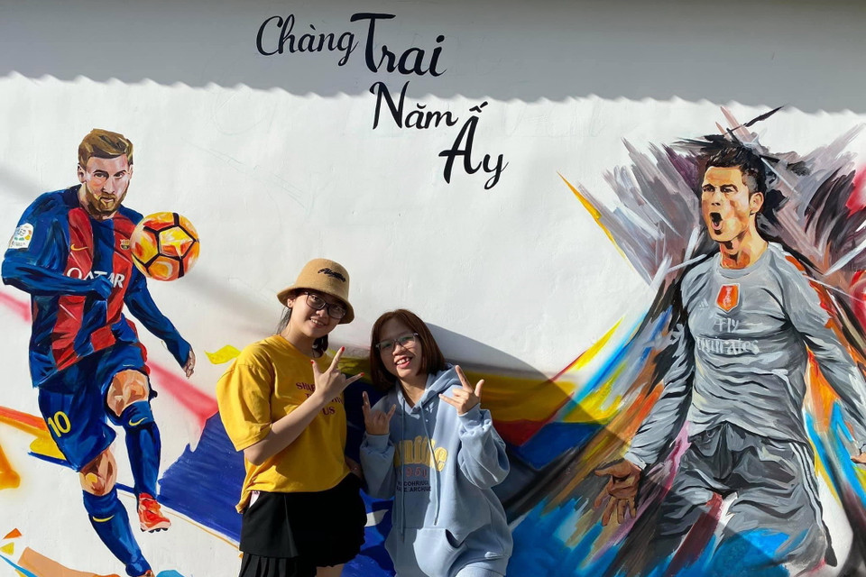 Du khách chụp ảnh lưu niệm với các bức bích họa. (Ảnh: TTXVN phát)