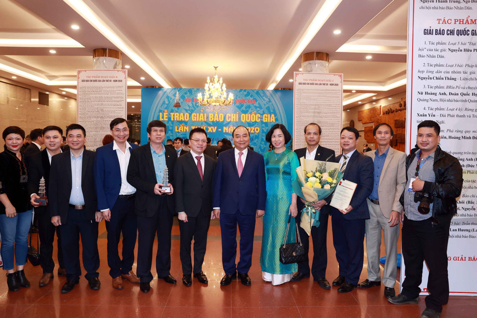 Chủ tịch nước Nguyễn Xuân Phúc, Tổng biên tập báo Nhân Dân Lê Quốc Minh và Tổng giám đốc TTXVN Vũ Việt Trang cùng các nhà báo của TTXVN. (Ảnh: Thống Nhất/TTXVN)