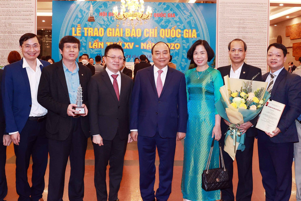 Chủ tịch nước Nguyễn Xuân Phúc, Tổng biên tập báo Nhân Dân Lê Quốc Minh và Tổng giám đốc TTXVN Vũ Việt Trang cùng các nhà báo của TTXVN. (Ảnh: Thống Nhất/TTXVN)