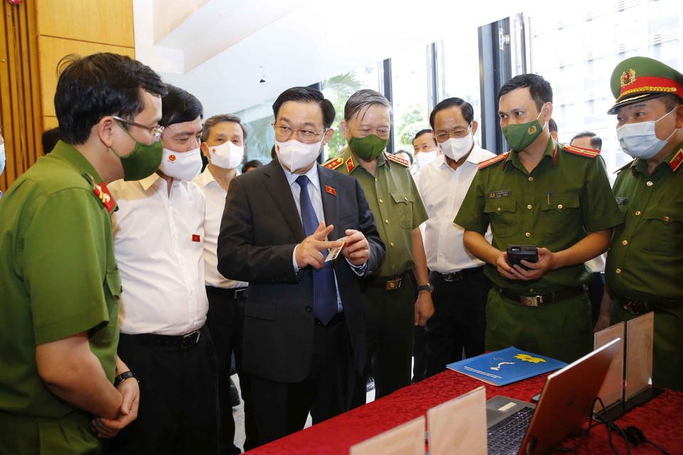 Chủ tịch Quốc hội Vương Đình Huệ nghe giới thiệu về tính năng hiện đại của căn cước công dân có gắn chíp điện tử. (Ảnh: Doãn Tấn/TTXVN)