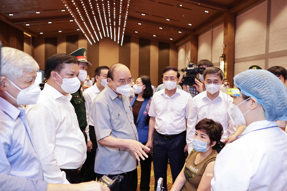 Chủ tịch nước Nguyễn Xuân Phúc thăm hỏi, động viên các nhân viên y tế làm nhiệm vụ tiêm vaccine phòng COVID – 19 cho nhân dân tại phường Bạch Đằng, quận Hai Bà Trưng, Hà Nội. (Ảnh: Thống Nhất/TTXVN) 