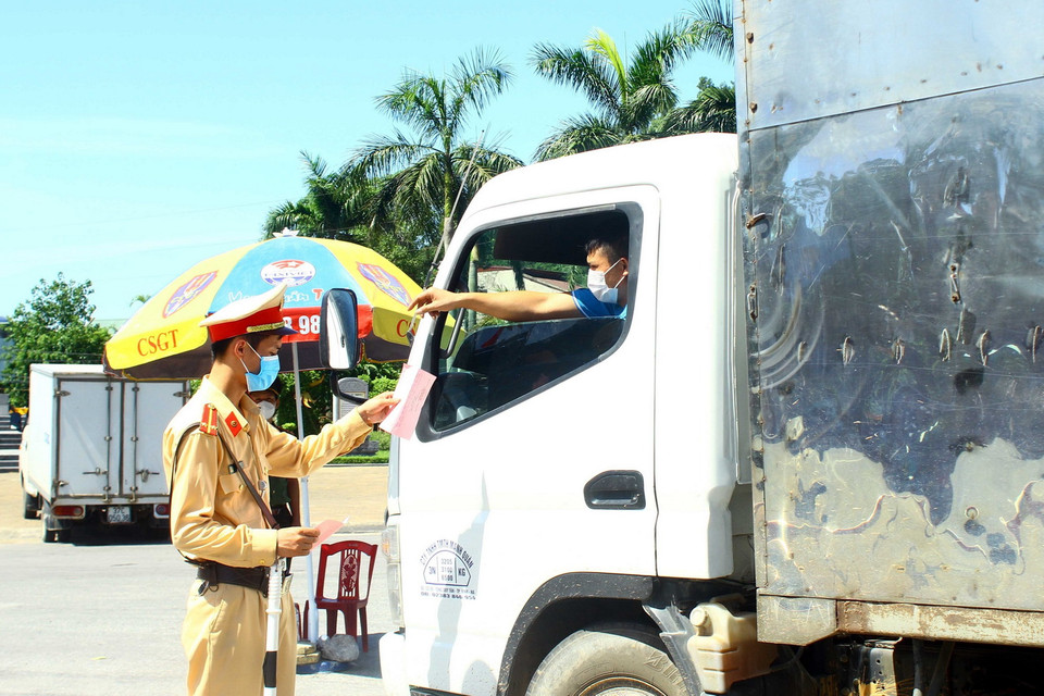  Cán bộ Cảnh sát giao thông thành phố Vinh kiểm tra giấy tờ của các chủ phương tiện khi qua chốt kiểm soát tại cầu Bến Thủy. (Ảnh: Tá Chuyên/TTXVN)