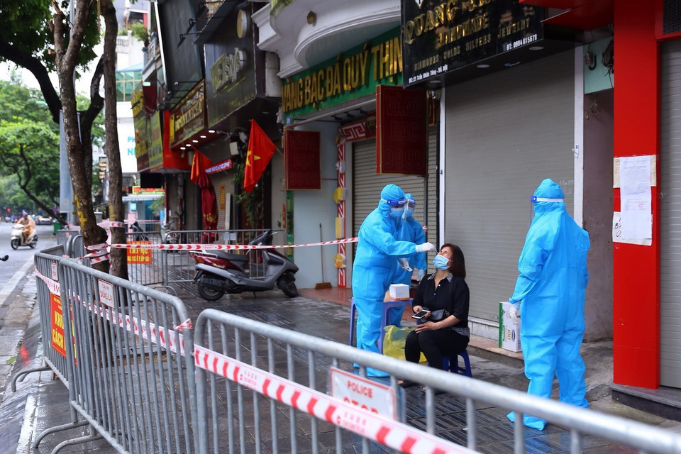 Người dân trong ngõ 21 Trần Nhân Tông được nhân viên y tế lấy mẫu xét nghiệm. (Ảnh: Hoàng Hiếu/TTXVN) 