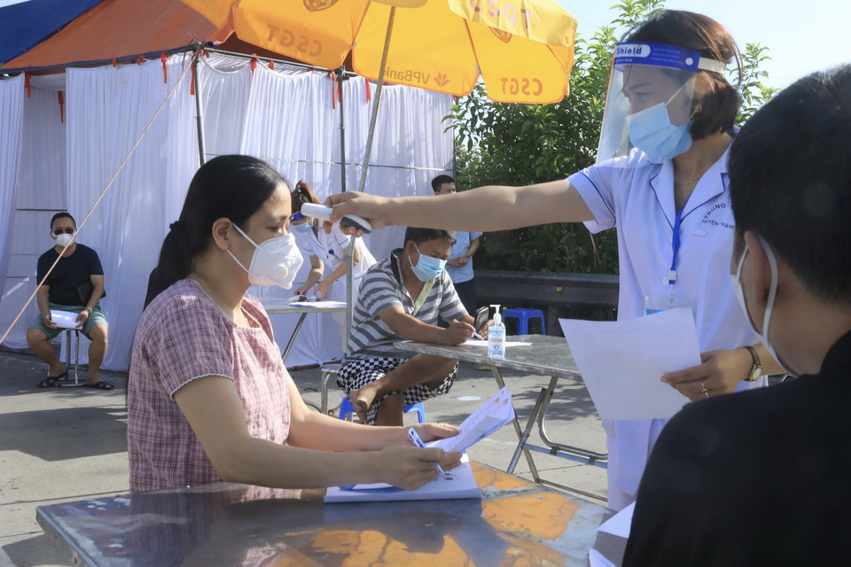 Lực lượng y tế kiểm tra thân nhiệt với những người đến từ vùng dịch. (Ảnh: Lâm Khánh/TTXVN)