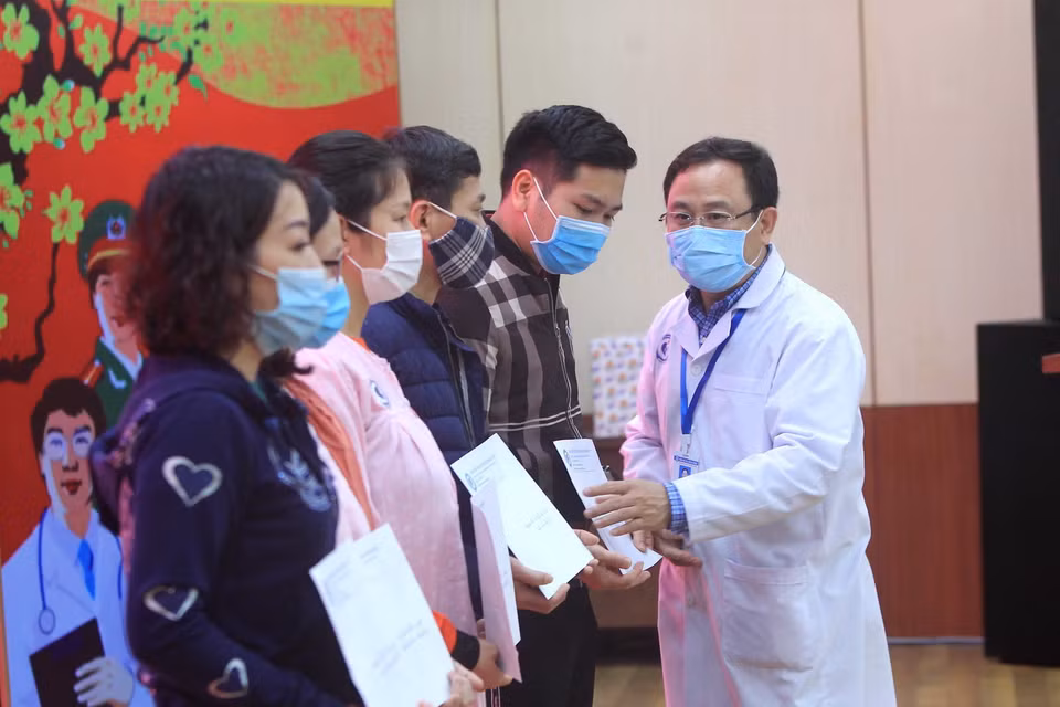 Đại diện gia đình các bệnh nhân nhận giấy chứng nhận ra viện. (Ảnh: An Đăng/TTXVN)