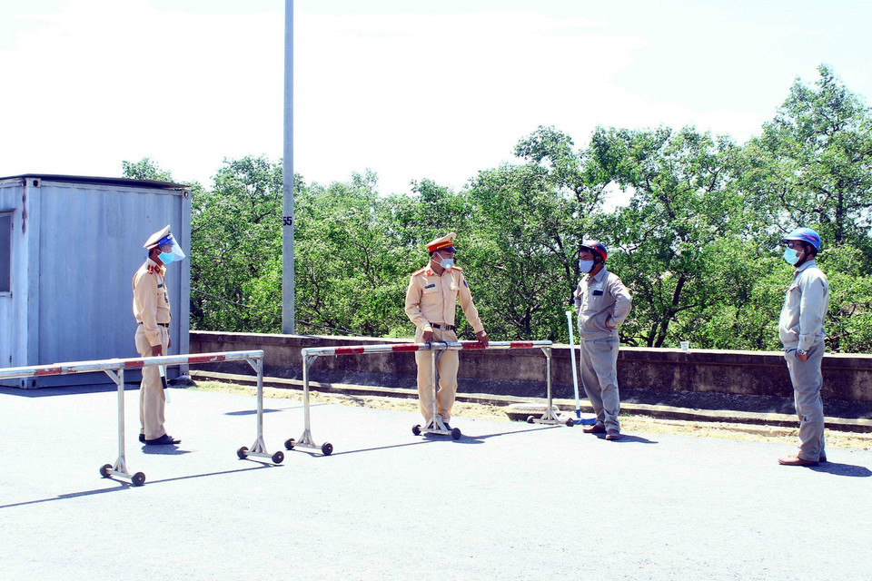  Cán bộ chiến sỹ Cảnh sát giao thông thành phố Vinh "căng mình" dưới nắng nóng để giải thích cho người dân không được qua chốt kiểm soát tại đê xã Hưng Hòa, thành phố Vinh, tỉnh Nghệ An khi không đầy đủ các giấy tờ theo quy định. (Ảnh: Tá Chuyên/TTXVN)