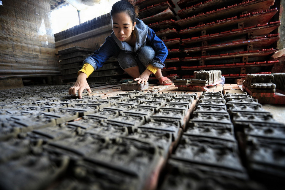 Để tượng không bị vỡ nát, hư hỏng, khi đưa tượng vào lò, người thợ cần phải sắp xếp thành từng hàng, nhiều lớp trên dưới xen kẽ, giữa các lối cần có khoảng cách để lửa cháy đều. (Ảnh: Thành Đạt/TTXVN)