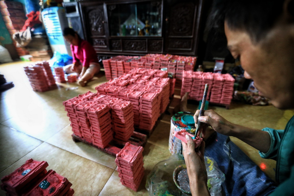 Sau khi nung, những bức tượng ông Táo được vẽ bằng màu rồi rắc bột kim tuyến để trông bắt mắt hơn. (Ảnh: Thành Đạt/TTXVN)