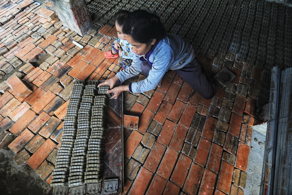 Để tượng không bị vỡ nát, hư hỏng, khi đưa tượng vào lò, người thợ cần phải sắp xếp thành từng hàng, nhiều lớp trên dưới xen kẽ, giữa các lối cần có khoảng cách để lửa cháy đều. (Ảnh: Thành Đạt/TTXVN)