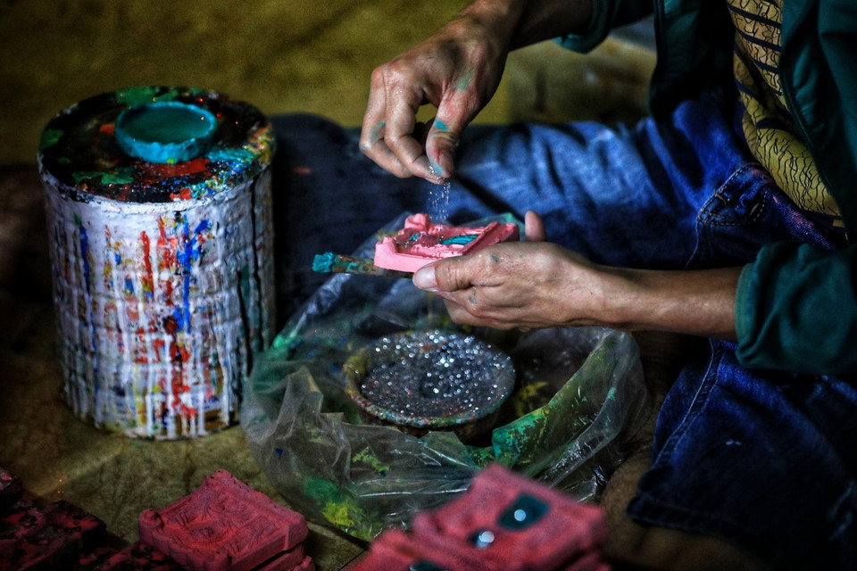 Sau khi nung, những bức tượng ông Táo được người dân vẽ bằng màu rồi rắc bột kim tuyến để trông bắt mắt hơn. (Ảnh: Thành Đạt/TTXVN)