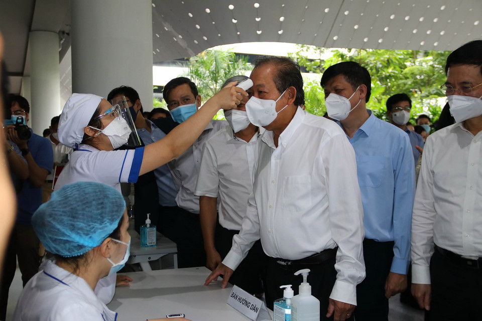  Phó Thủ tướng thường trực Chính phủ Trương Hòa Bình đo thân nhiệt tại lễ khởi động chiến dịch tiêm chủng vaccine phòng COVID-19 tại TP Hồ Chí Minh. (Ảnh: Thanh Vũ/TTXVN)
