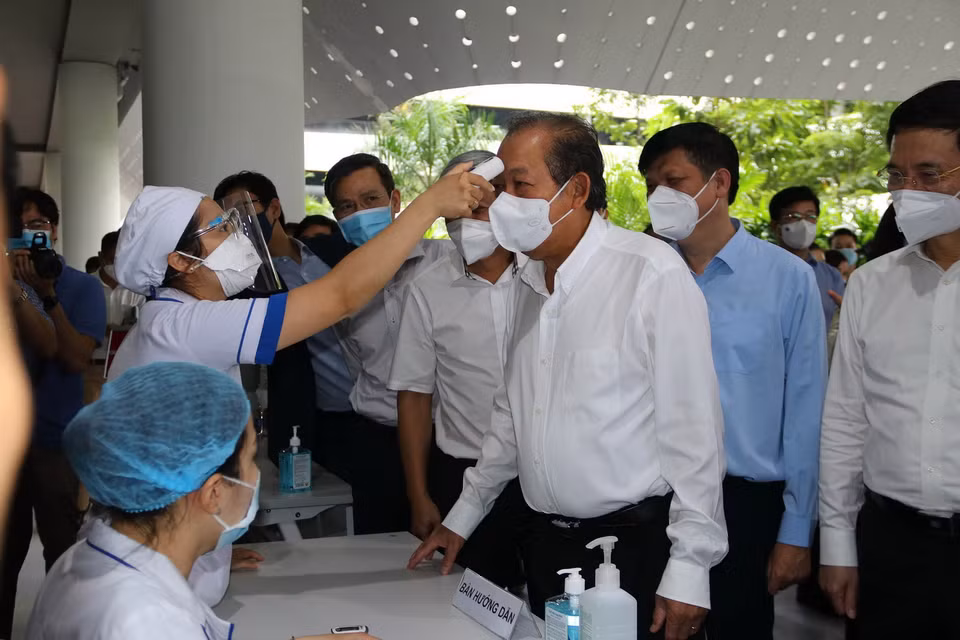  Phó Thủ tướng thường trực Chính phủ Trương Hòa Bình đo thân nhiệt tại lễ khởi động chiến dịch tiêm chủng vaccine phòng COVID-19 tại TP Hồ Chí Minh. (Ảnh: Thanh Vũ/TTXVN)