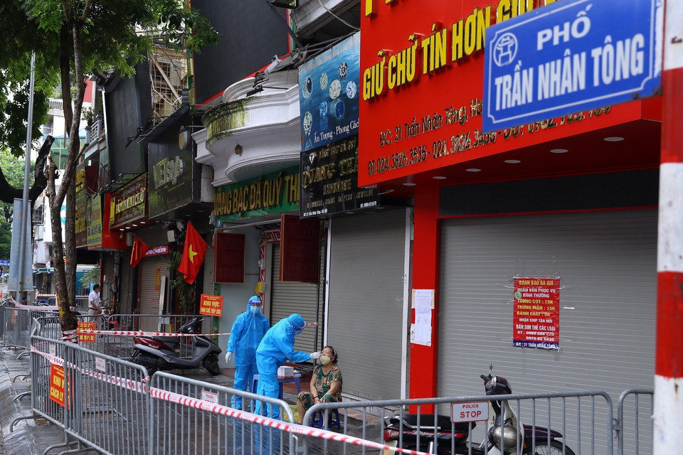 Liên quan đến ca F0 ở số 21 Trần Nhân Tông, nhân viên y tế lấy mẫu xét nghiệm cho người dân. (Ảnh: Hoàng Hiếu/TTXVN) 