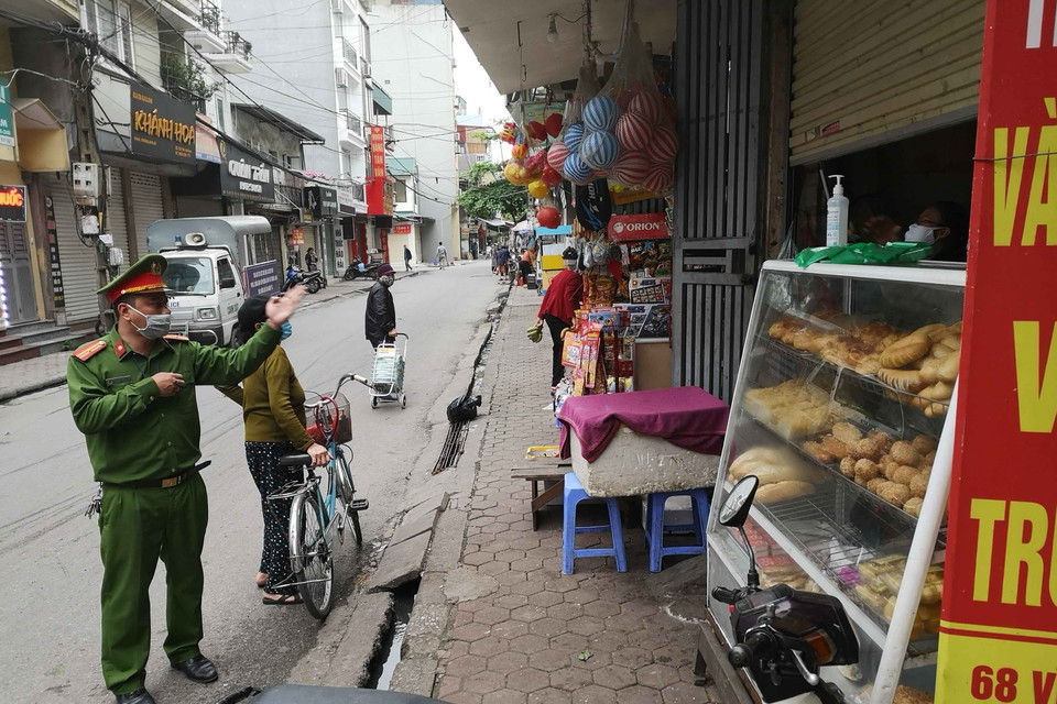 Công an phường Vĩnh Tuy (Hai Bà Trưng) nhắc nhở người dân, hộ kinh doanh thực hiện đúng chỉ thị của Thủ tướng Chính phủ. (Ảnh: Thanh Tùng/TTXVN)