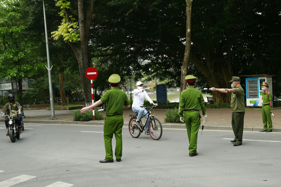Công an quận Hoàn Kiếm lập chốt, tuyên truyền người dân ở nhà, hạn chế tối đa ra ngoài tập thể dục tại khu vực Hồ Hoàn Kiếm. (Ảnh: Doãn Tấn/TTXVN)
