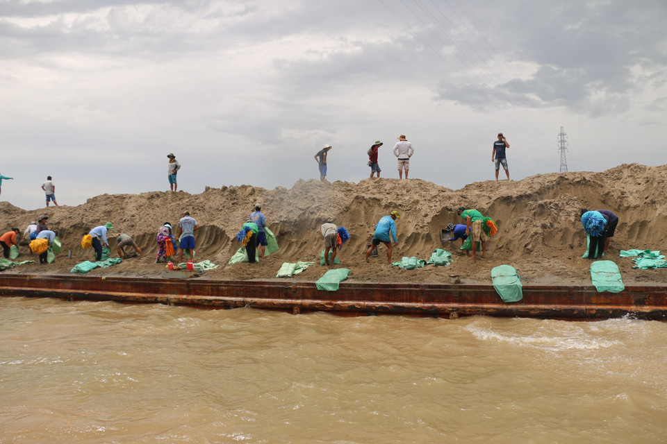 Các đơn vị chức năng đang huy động hàng trăm công nhân thả bao cát xuống để gia cố đường bờ, hạn chế sạt lở. (Ảnh: Công Mạo/TTXVN)