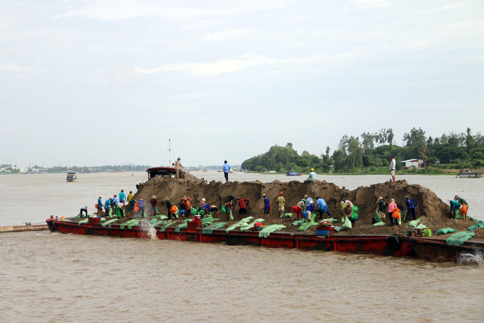 Lực lượng chức năng thả bao cát gia cố đường bờ, hạn chế sạt lở. (Ảnh: Công Mạo/TTXVN)