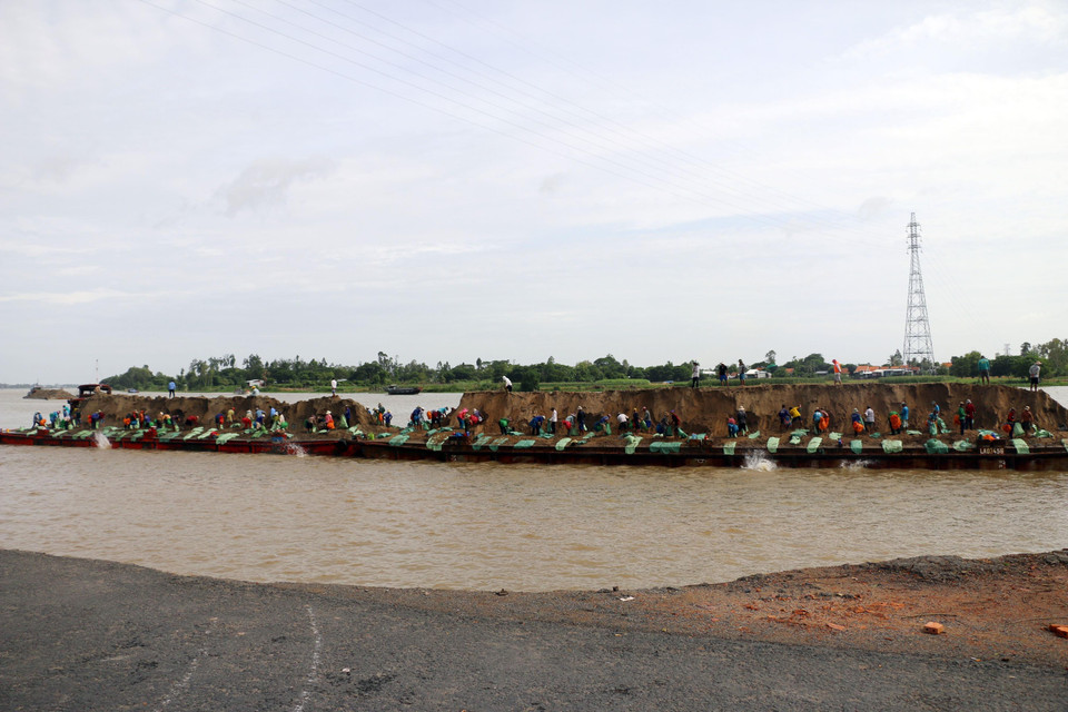 Lực lượng chức năng thả bao cát gia cố đường bờ, hạn chế sạt lở. (Ảnh: Công Mạo/TTXVN)