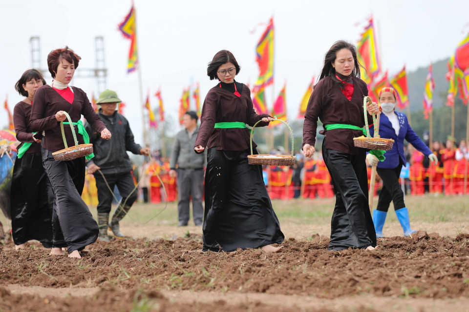 Các thôn nữ đi sau gieo hạt giống để cầu mong một năm mới với mùa màng tươi tốt bội thu. (Ảnh: Thanh Tùng/TTXVN)