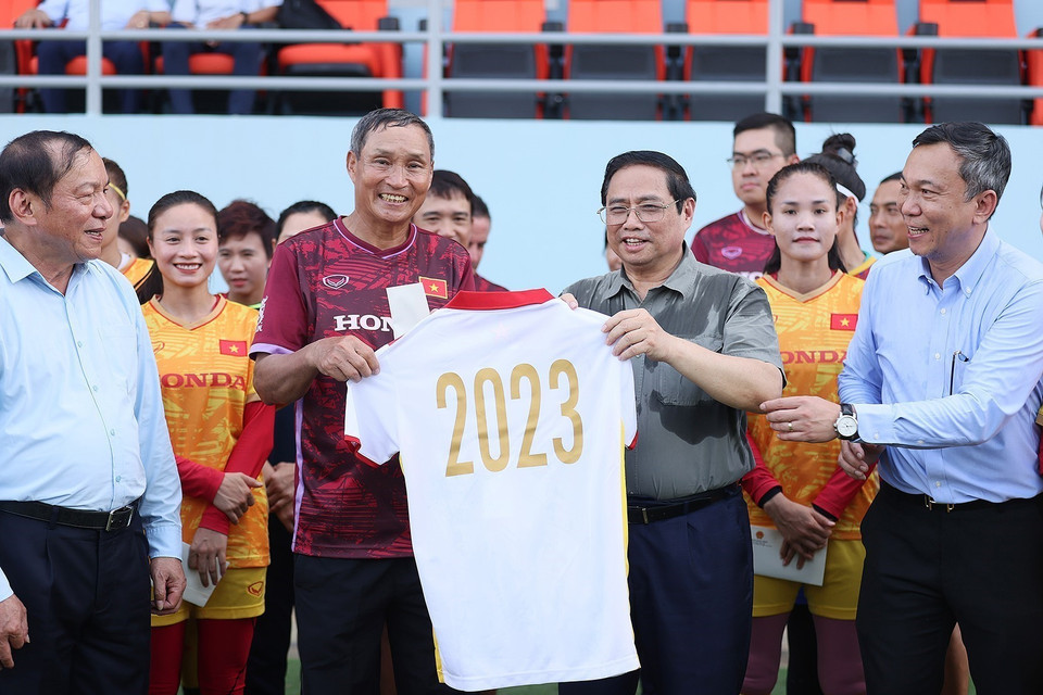 Huấn luyện viên Mai Đức Chung, đại diện Tuyển Nữ Việt Nam tặng Thủ tướng Phạm Minh Chính chiếc áo thi đấu của có chữ ký của toàn Đội. (Ảnh: Dương Giang/TTXVN)