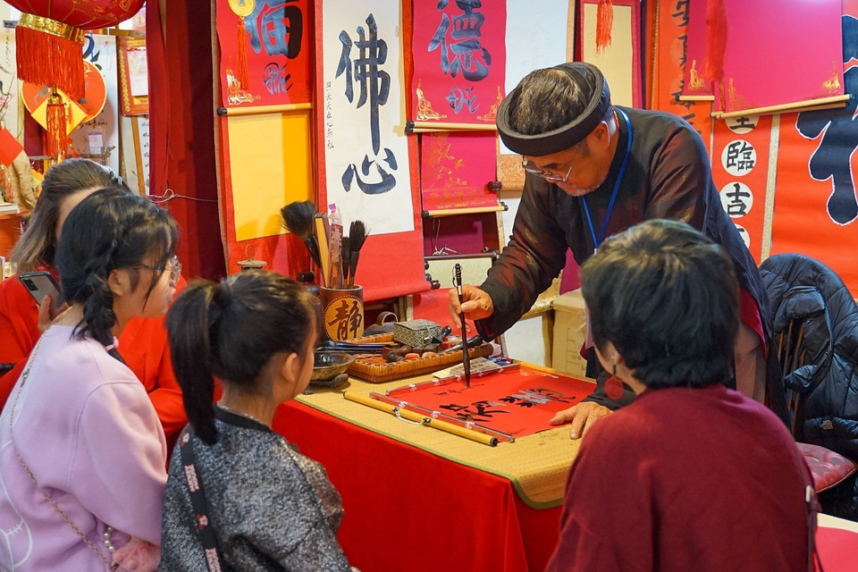 Các bạn nhỏ chăm chú xem ông đồ cho chữ tại Hồ Văn-Văn Miếu Quốc Tử Giám ngày mùng 2 Tết Quý Mão. (Ảnh: Khánh Hòa/TTXVN)