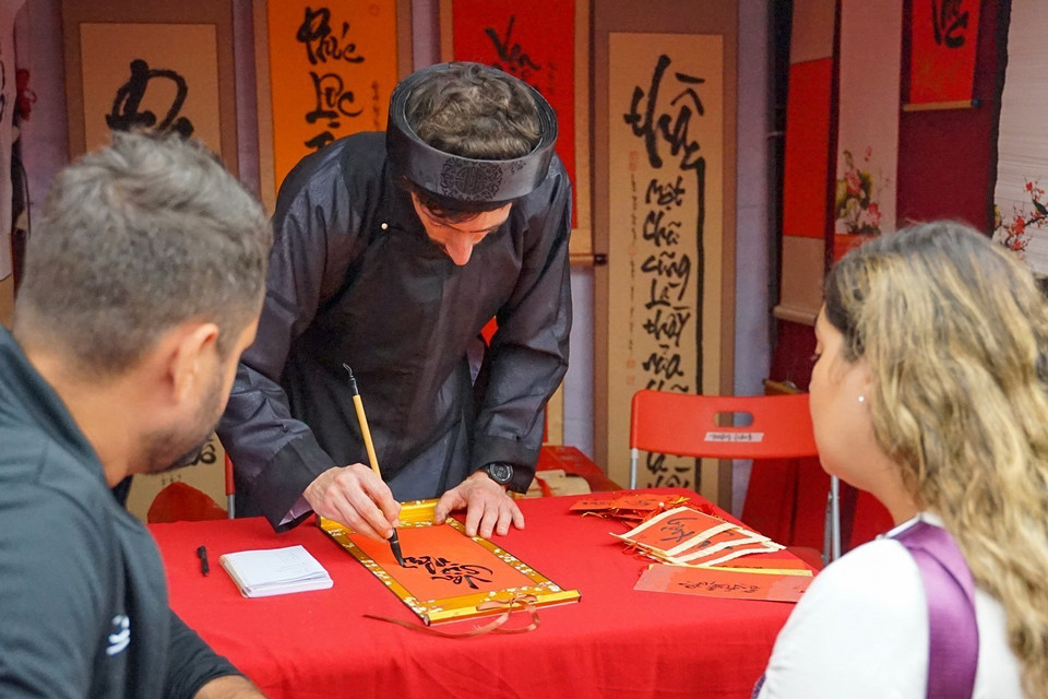 Gian 'ông đồ Tây' ở Hội chữ Xuân Quý Mão 2023 thu hút rất nhiều du khách nước ngoài đến xin chữ. (Ảnh: Khánh Hòa/TTXVN)